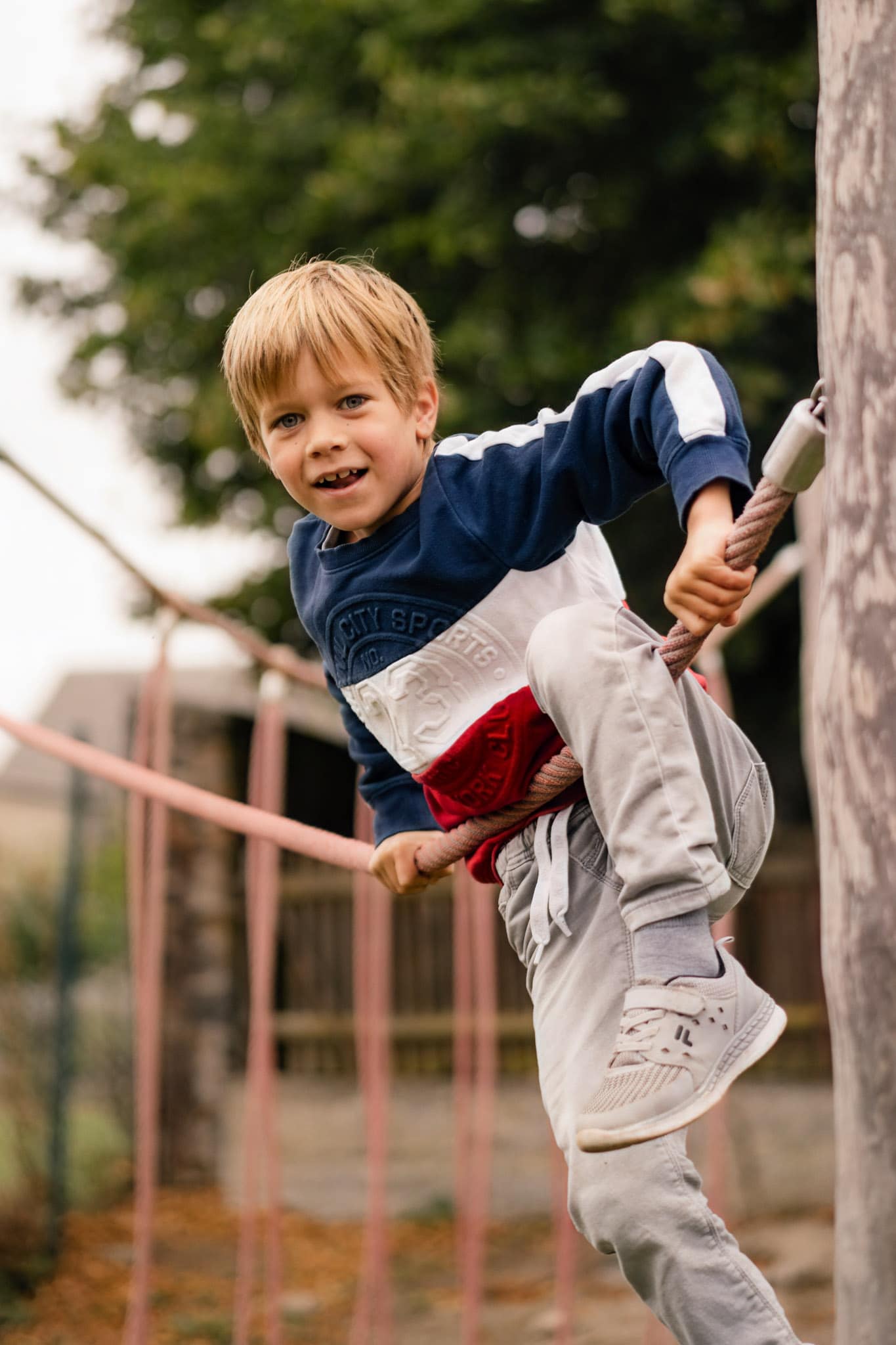 Grundschulfoto von einem Jungen, der an einem Klettergerüst in der Grundschule klettert.